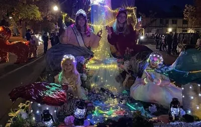 Four people in glowing fairy costumes on a decorated night parade float