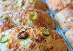 Close-up of golden baked rolls topped with jalapeño slices and melted cheese