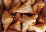 Golden fried samosas piled together in a basket