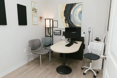 Small medical office with white desk, gray chairs, and abstract wall art