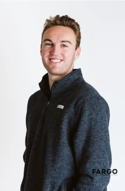 Smiling young man in a dark navy quarter-zip fleece against a white background