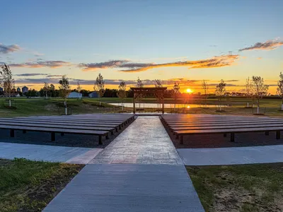 Outdoor venue amphitheater with tiered seating platforms leading to a pergola at sunset