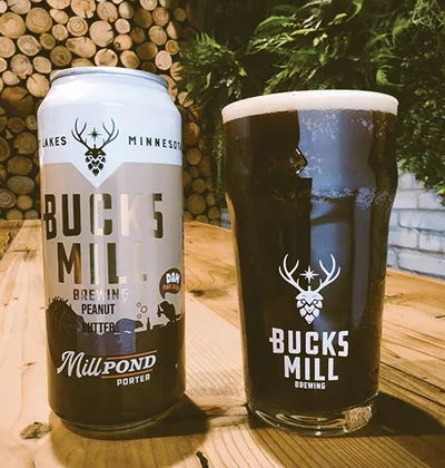Bucks Mill Brewing Peanut Butter Mill Pond Porter can beside a full pint glass on a wood table
