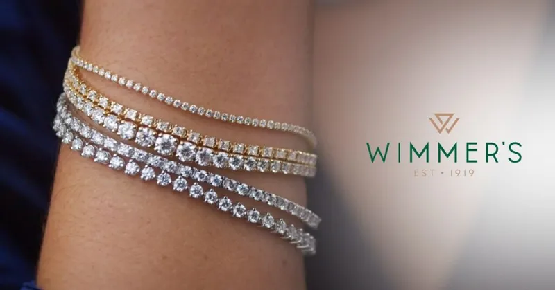 Four diamond tennis bracelets in gold and silver tones stacked on a wrist