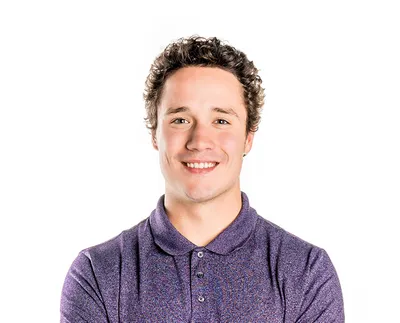 Smiling young man with curly hair wearing a purple polo shirt