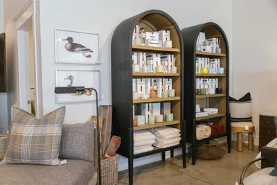 Two black arched shelving units displaying home goods beside duck artwork and a plaid sofa