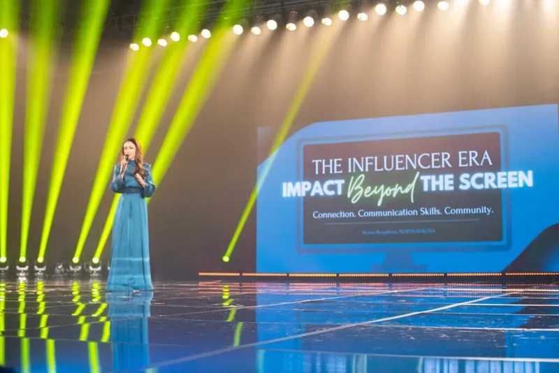 Woman in teal gown speaks on stage before a screen reading 'The Influencer Era: Impact Beyond the Screen