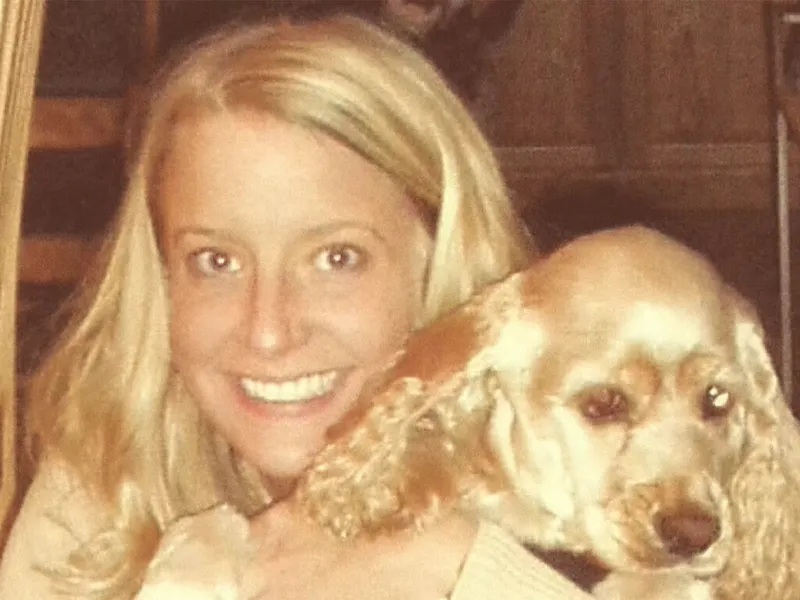 Smiling blonde woman cheek-to-cheek with a golden cocker spaniel in a warm-toned vintage photo