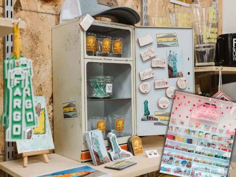 Vintage mini fridge display with Fargo-themed souvenirs, magnets, glasses, and postcards in a retail shop