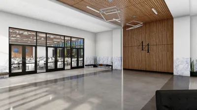 Modern event venue lobby with wood-slat accent wall, polished concrete floors, and glass-paneled doors opening to a banquet