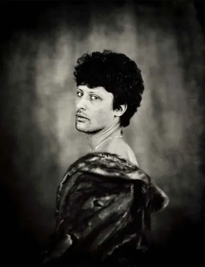 Black-and-white wet plate portrait of a man in a fur wrap glancing over his shoulder