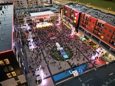 Aerial view of a large outdoor concert crowd in an urban plaza at dusk