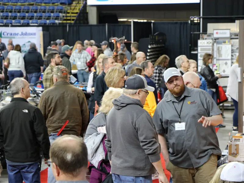 Crowded indoor home show expo floor with vendors and attendees browsing exhibits