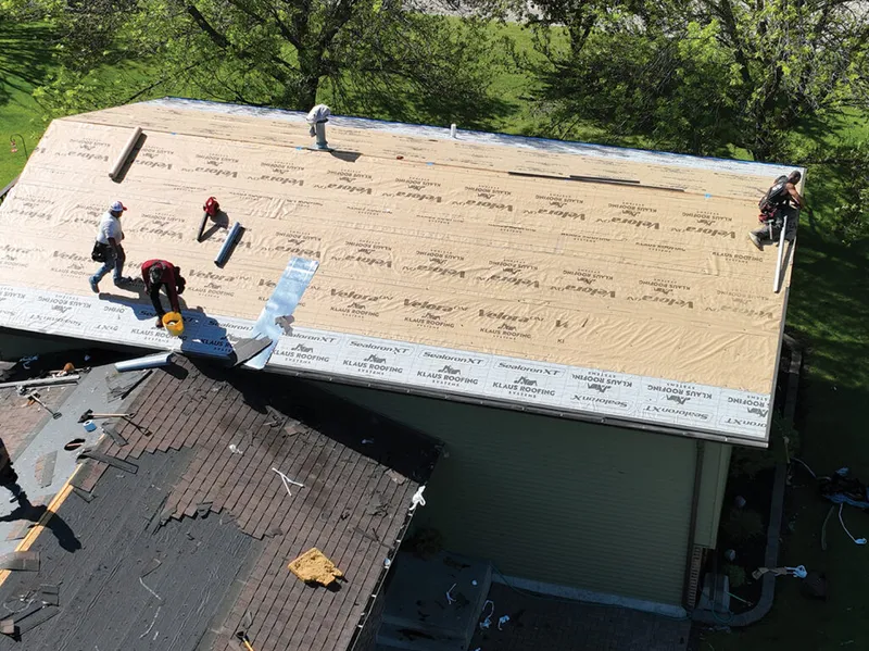 Aerial view of roofers laying underlayment on a large residential roof
