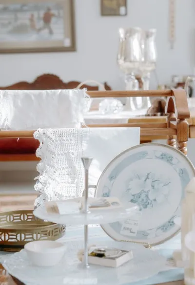 Vintage china plate and white lace linens displayed at a consignment shop