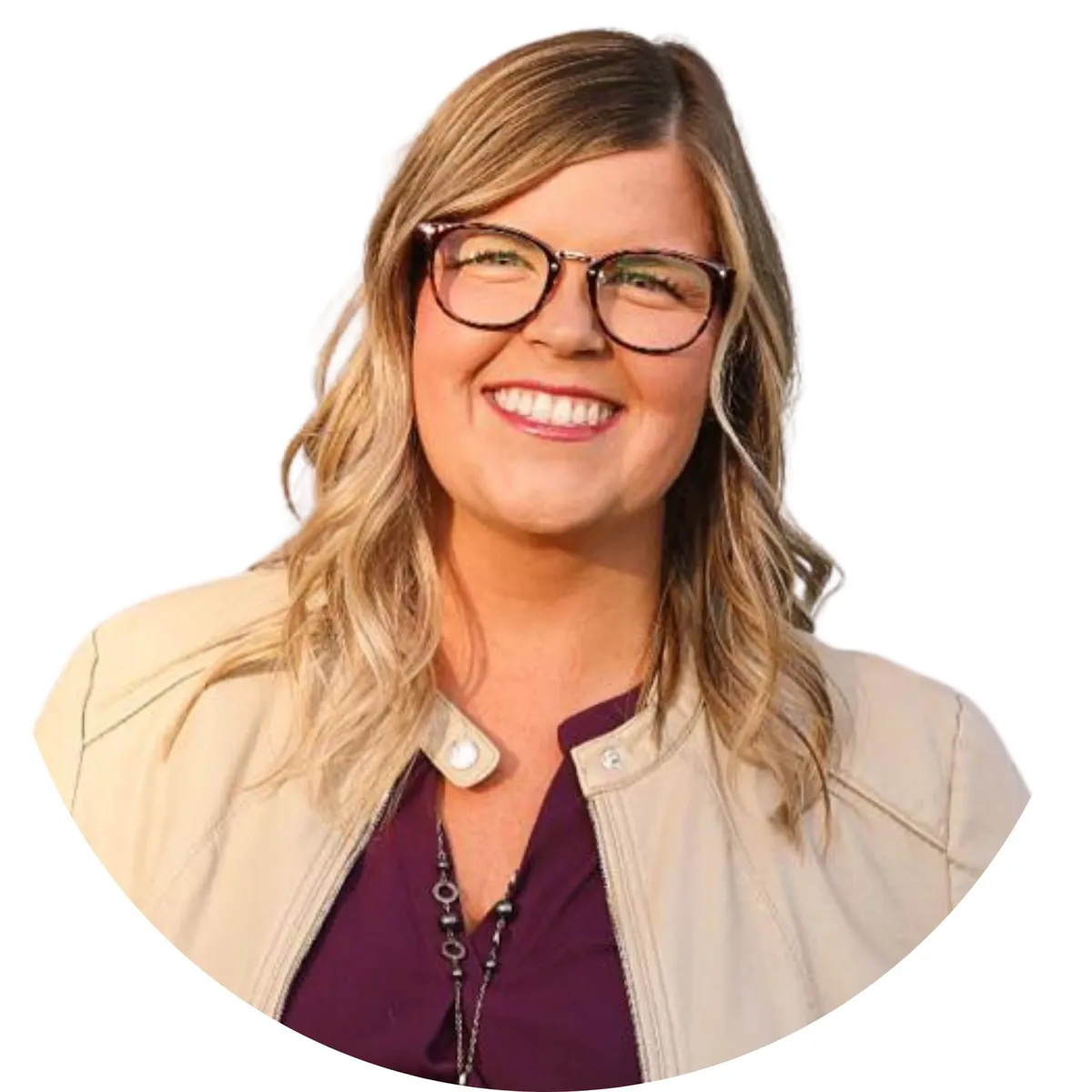 Smiling woman with blonde wavy hair and tortoiseshell glasses wearing a cream jacket and burgundy top