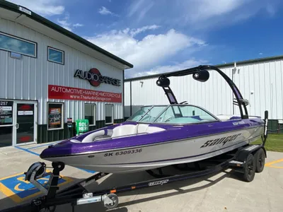 Purple wakeboard boat on trailer parked outside Audio Garage storefront