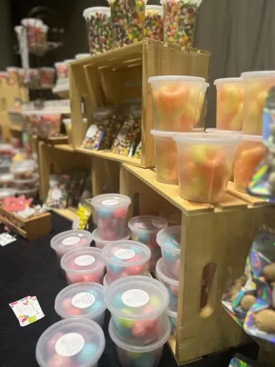 Plastic cups of colorful freeze-dried candy displayed on a wooden crate shelf