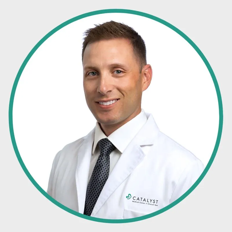 Man in white Catalyst Medical coat and dark tie smiling in a circular headshot