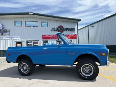 Bright blue classic lifted SUV parked outside an Audio Garage shop
