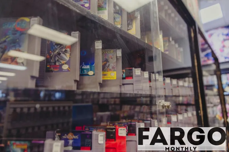 Glass display case filled with retro video game cartridges and boxed games on store shelves