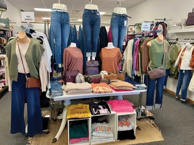 Boutique display with mannequins in casual tops and jeans, folded clothes on a center table
