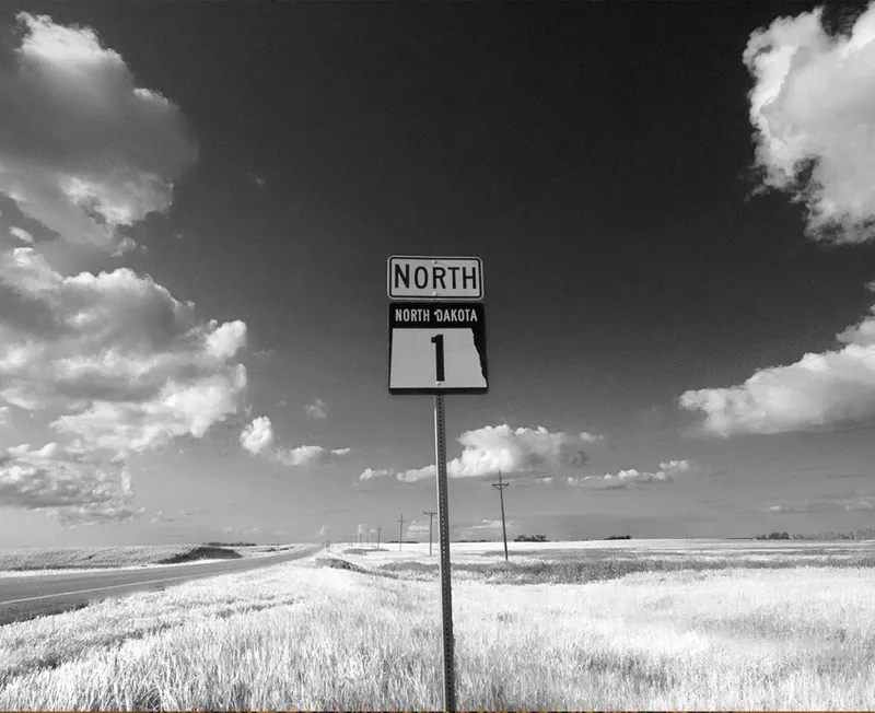 Black-and-white photo of North Dakota Route 1 North road sign amid flat grassland