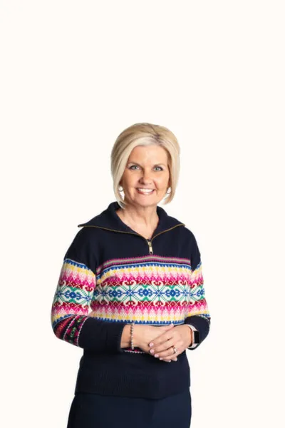 Smiling woman with short blonde hair wearing a colorful fair isle zip-neck sweater