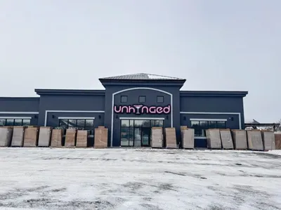 Unhinged storefront with large signage, surrounded by snow and stacked crates outside