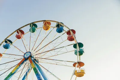 Colorful ferris wheel with multicolored gondolas against a pale sky