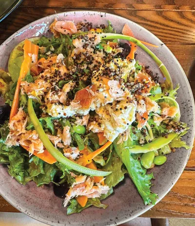 Salmon and quinoa salad with edamame, shredded carrots, and mixed greens on a ceramic plate