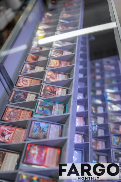 Rows of trading cards sorted in tiered display bins inside a glass showcase