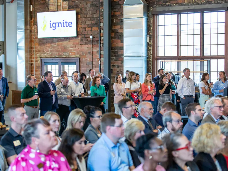 Crowd of professionals attending an Ignite event in a brick-walled industrial venue