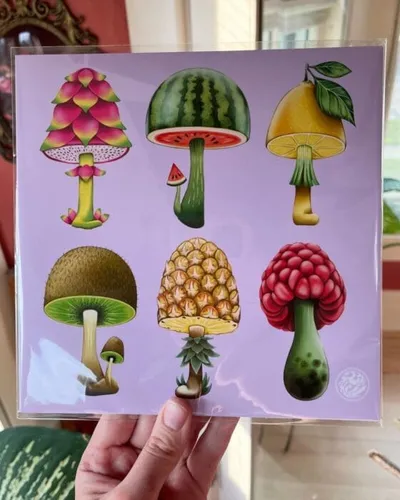 Hand holding a purple art print featuring six whimsical mushrooms with fruit-themed caps