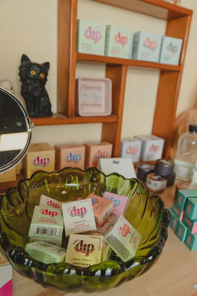 Green glass bowl filled with small dip-branded product boxes on a retail display shelf