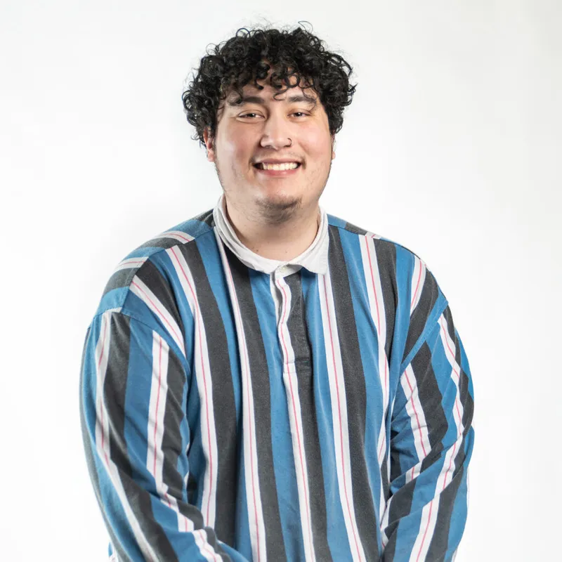Smiling young man with curly dark hair wearing a blue and gray striped shirt