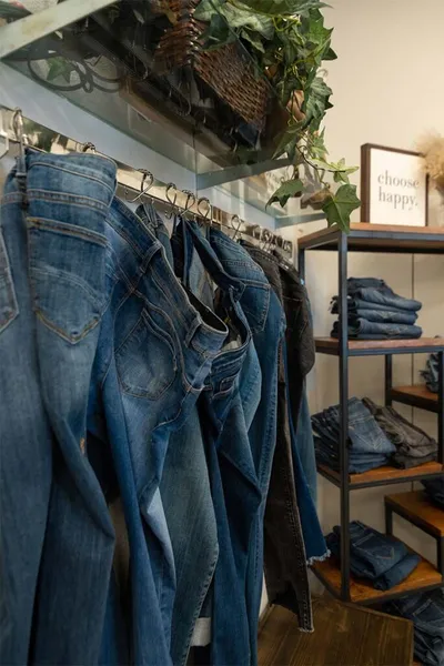 Denim jeans hanging on a rack beside a shelf of folded jeans in a cozy boutique