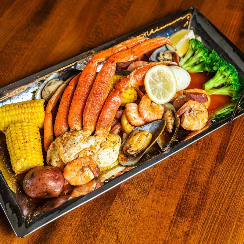 Seafood boil platter with crab legs, shrimp, mussels, corn, potatoes, and broccoli