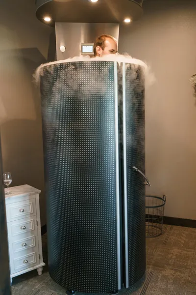 Man inside a cryotherapy chamber with cold vapor rising around his head