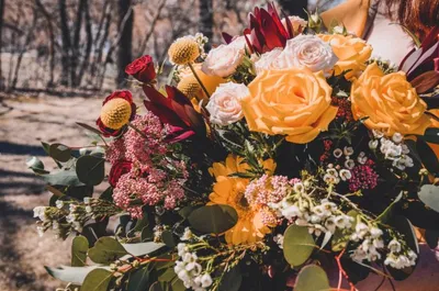 Lush bridal bouquet with yellow and white roses, red blooms, and eucalyptus foliage