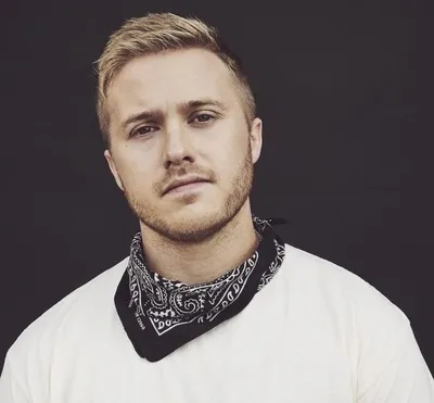Young blond man with stubble wearing a white tee and black paisley bandana