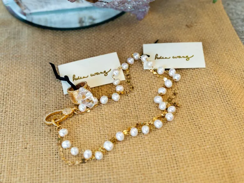 Pearl and gold chain bracelet and earrings with crystal accents on burlap
