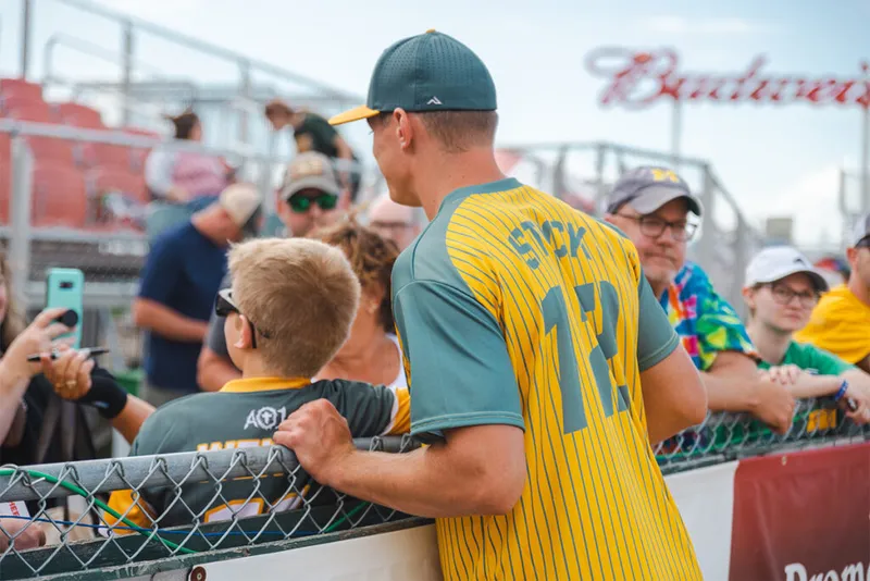 Baseball player in yellow pinstripe jersey numbered 17 greeting fans at a railing