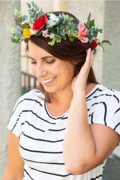 Smiling woman wearing a colorful floral crown and striped tee