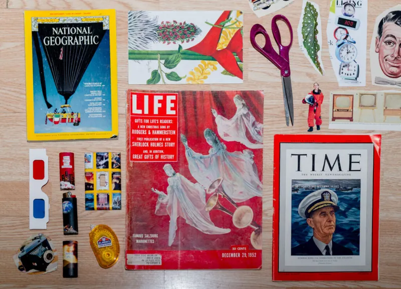 Flat lay of vintage magazines, red 3D glasses, scissors, lighters, and paper cutouts on a wood surface