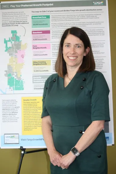Woman in green dress standing before a Fargo city growth planning display board
