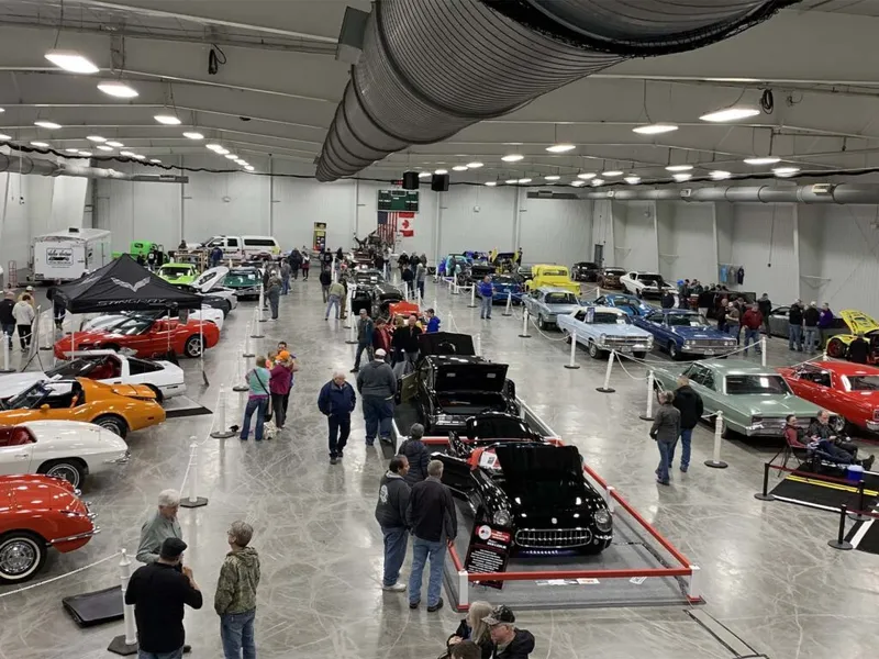 Crowds browse rows of classic and vintage cars inside a large indoor auto show