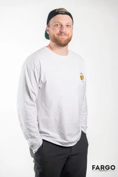 Smiling bearded man in a white long-sleeve shirt and backward cap