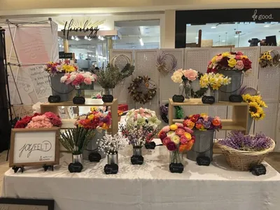 Colorful felt flower bouquets displayed on a tiered vendor market table