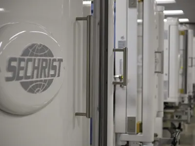 Row of white Sechrist hyperbaric chambers with metal handles in a clinical facility